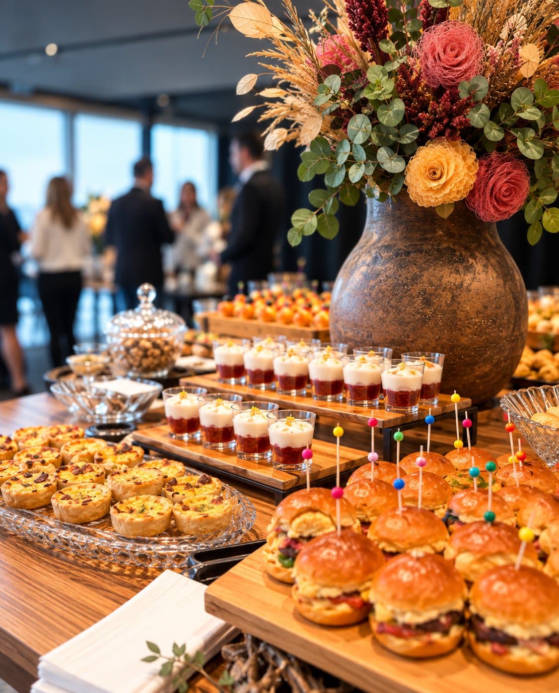 Mesa de buffet com arranjo floral em evento corporativo com convidados